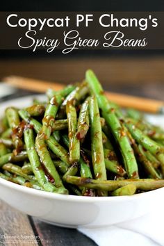 a white bowl filled with green beans on top of a wooden table