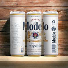 three cans of modelo beer on a wooden shelf