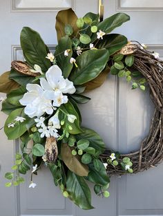 a wreath with white flowers and green leaves hangs on the front door to welcome guests