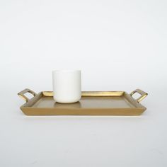 a gold tray with a white cup on it