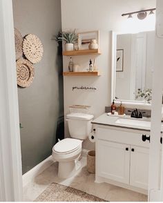 a white toilet sitting in a bathroom next to a sink and shower stall with baskets on the wall