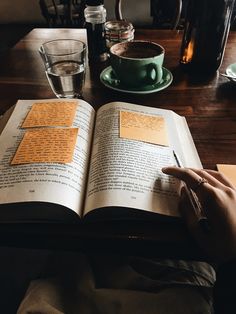 a person sitting at a table with an open book in front of them and a cup of coffee