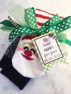 a sock with a santa clause on it is tied to a green bow and has a card that says send merry for your mistleties