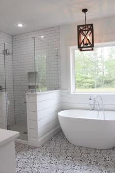 a white bath tub sitting under a window next to a sink and shower in a bathroom