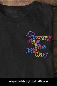 a black t - shirt with the words every dog has today embroidered on it's chest