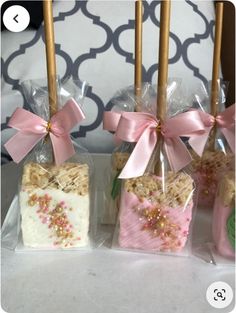 four small candy bars wrapped in cellophane and tied with pink ribbon, sitting next to each other