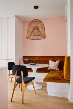 two chairs and a table in a room with pink paint on the walls, wood flooring