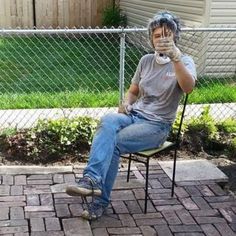 a man sitting in a chair with his hands up to his face