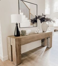 a wooden table with two vases on top of it next to a stair case