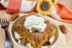 a piece of cake on a plate with whipped cream and pecans next to it