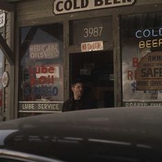 a man standing in the window of a cold beer shop