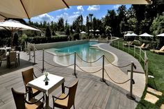 an outdoor swimming pool surrounded by tables and chairs