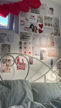 a bed with lots of pictures on the wall above it and a red heart hanging from the headboard