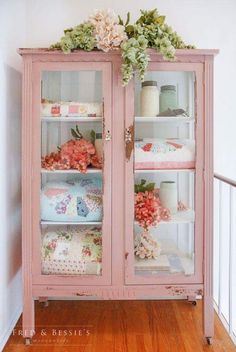 a pink china cabinet with flowers on top