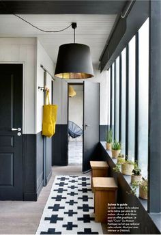 a hallway with black and white checkered flooring, hanging lights and potted plants