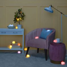 a purple chair sitting in front of a table with lights on it and a potted plant