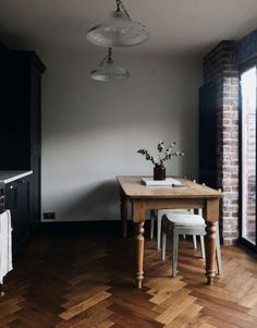 a kitchen with wooden floors and black cabinets, white chairs and a table in the middle