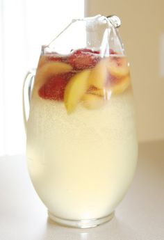 a pitcher filled with ice and fruit on top of a table