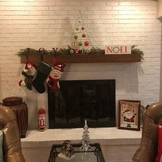 two chairs and a table in front of a fireplace with stockings on the mantel