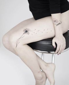 a woman is sitting on a stool with her legs crossed and tattoos on the leg