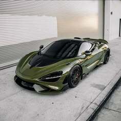 a green sports car parked in front of a garage