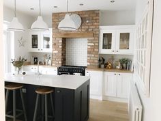 a kitchen with two bar stools next to an island in front of a brick wall