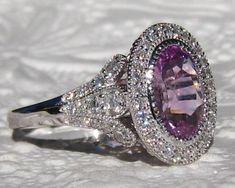 A beautiful and elaborate white gold engagement ring, featuring a sparkly untreated purplish pink sapphire, set in my Iris mount with a diamond halo. The center stone in a beautiful Ceylon sapphire with a violetish pink color. The oval sapphire weighs 2.48 carats and measures 10x7.4mm. It is eye-clean and completely untreated and comes with a GIA report. A great one-of-a-kind gem for an engagement ring or any special occasion! The sapphire is set in a beautiful and elegant 14K white gold IRIS ri Oval Purple Platinum Rings, Purple Oval Sapphire Ring, Brilliant Cut, Purple Oval Sapphire Ring With Brilliant Cut, Purple Brilliant Cut Oval Sapphire Ring, Oval Purple Sapphire Ring With Diamond, Purple Diamond Engagement Ring, Purple Diamond Ring, Iris Ring, Luxury Stuff