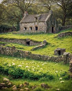 an old stone house sitting on top of a lush green hillside