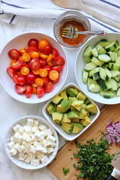 several bowls filled with different types of vegetables on top of a table next to a cutting board