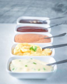 four different types of sauces and condiments in white dishes