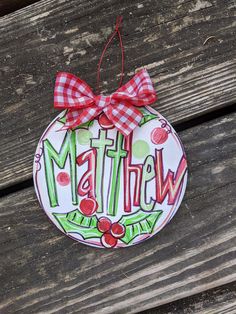 a christmas ornament hanging on a wooden bench with the word'mathew'painted on it