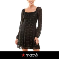 a woman wearing a black dress with polka dots on it and smiling at the camera