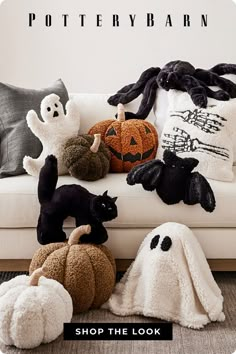 stuffed animals and pumpkins on a white couch in a living room with halloween decorations