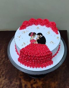 a wedding cake decorated with red roses and a couple on top is sitting on a table