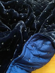 a blue sleeping bag with stars on it sitting on a wooden floor next to a black blanket