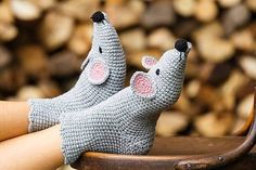 two small knitted mice sitting on top of a wooden chair next to firewood