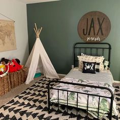 a bedroom with a teepee tent and stuffed animals in the corner, next to a black metal bed frame