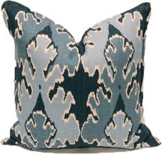 a blue and white pillow with an intricate design on the front, sitting on a white background