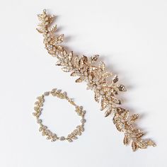 two pieces of jewelry sitting on top of a white surface