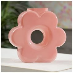 a pink flower shaped vase sitting on top of a table