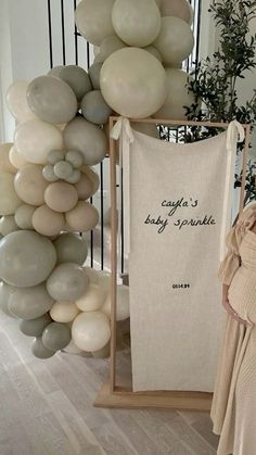 there is a baby sprinkle hanging on the wall next to balloons and a sign