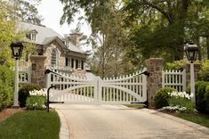 a driveway with a white gate leading to a house