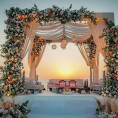 an outdoor wedding set up with white and pink flowers on the stage, overlooking the ocean