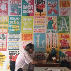 a man sitting at a desk in front of a wall covered with posters and letters