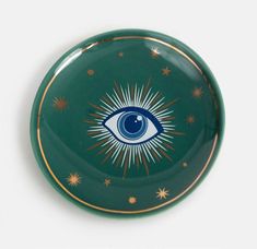 a green and gold plate with an eye painted on the side, surrounded by stars