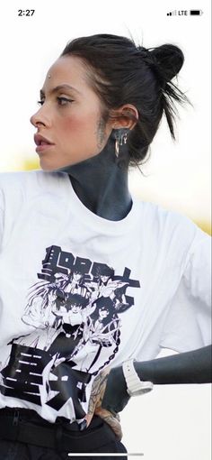 a woman with black hair and piercings wearing a white shirt