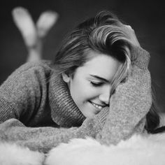 a black and white photo of a woman laying on the floor with her hands behind her head