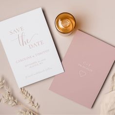 wedding save the date cards on a table next to a gold cup and vase with flowers