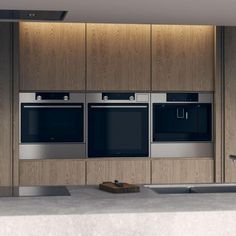 an empty kitchen with stainless steel appliances and wood paneling on the wall behind it