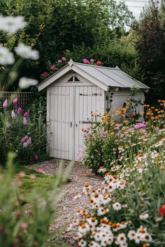 a garden with flowers and a shed in the middle, surrounded by greenery on both sides